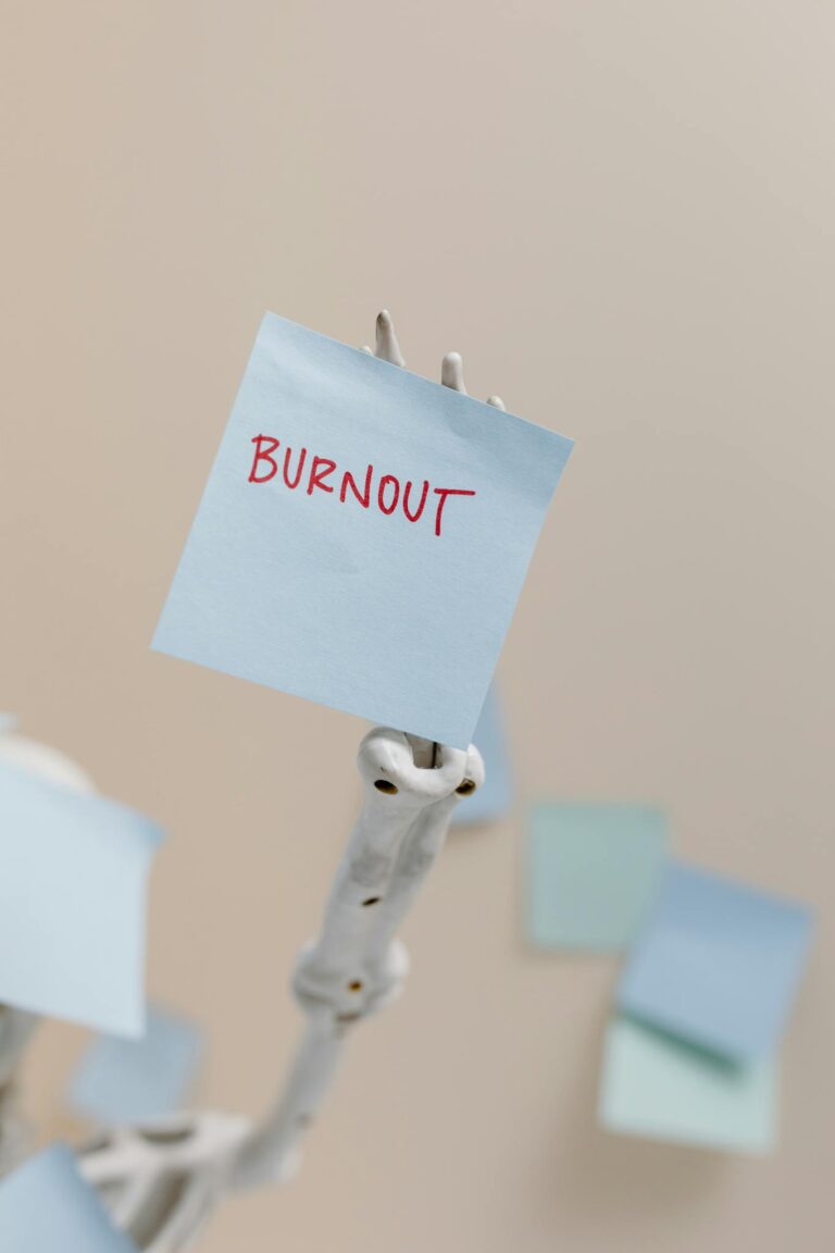 A skeleton holding a sticky note reading 'Burnout', symbolizing workplace stress.