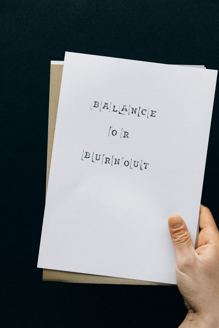 Close-up of a hand holding paper with text 'Balance or Burnout' symbolizing work-life decisions.